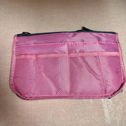 Pink mesh pouch on a beige textured surface