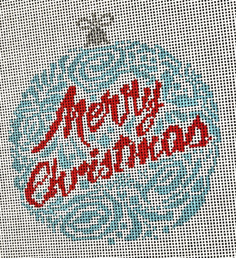 Cross-stitched 'Merry Christmas' text on fabric with a snowflake pattern.