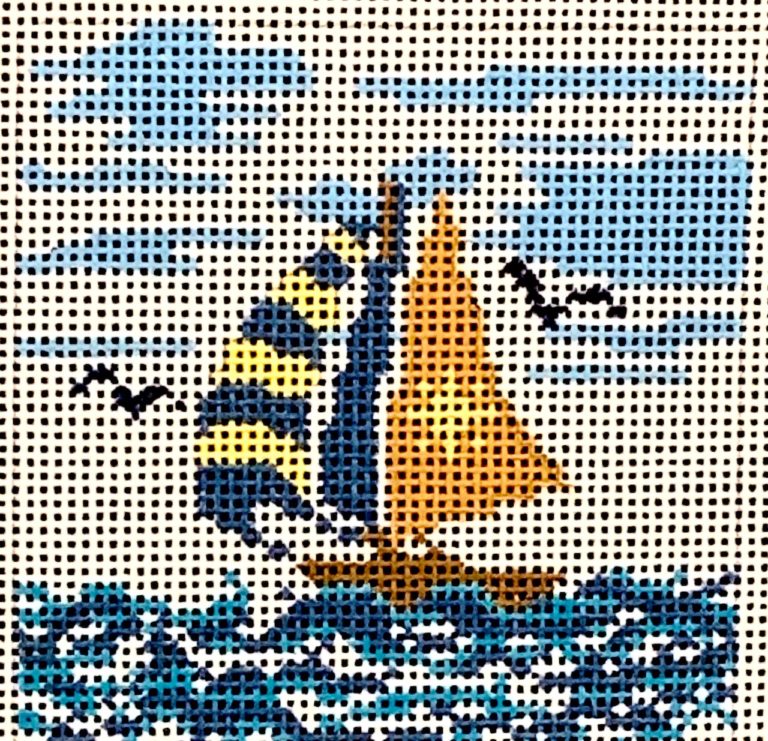Cross-stitched sailboat design on fabric with a blue ocean background