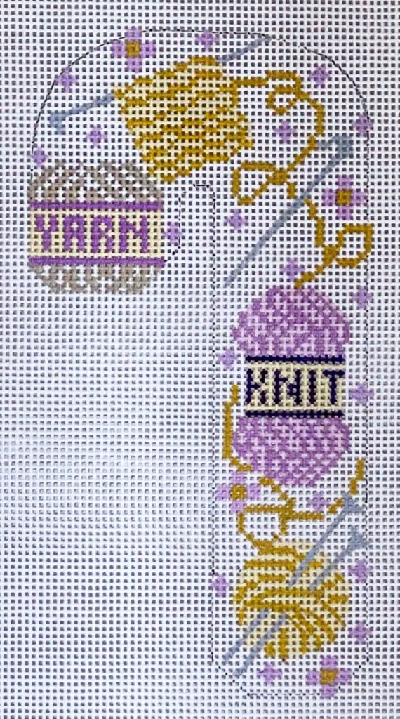 Cross-stitched design of a purple yarn ball with knitting needles on a white background