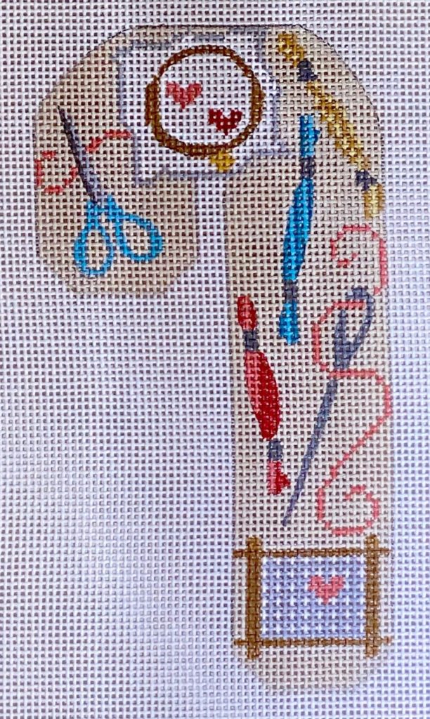 Cross-stitched design with sewing tools and materials on a white background