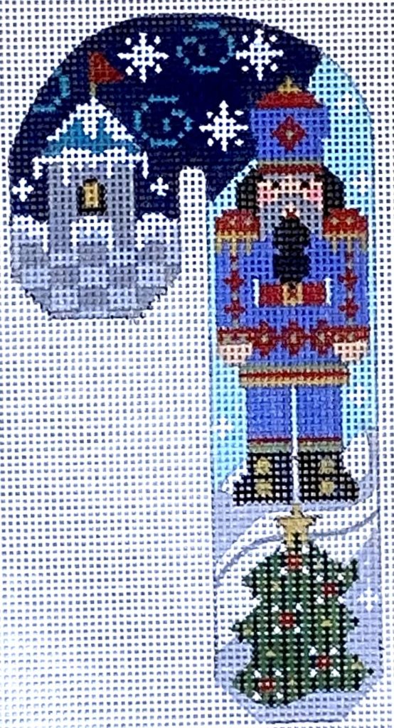 Decorative Christmas ornament with a nutcracker, tree, and house design.