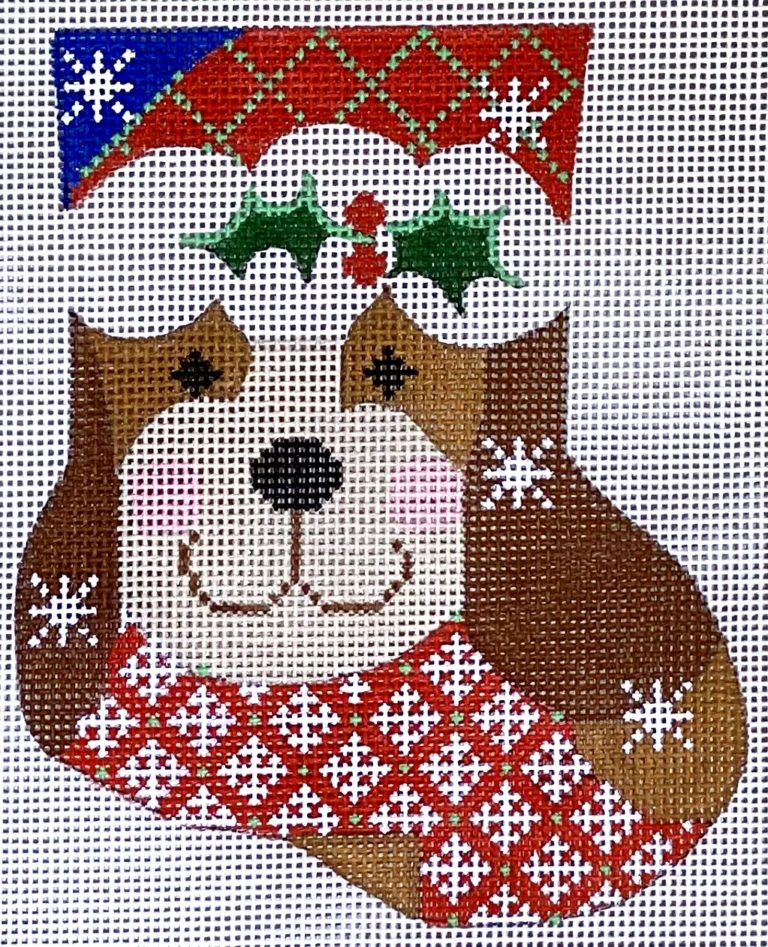 Decorative needlepoint of a dog wearing a festive hat with holly leaves and snowflakes.
