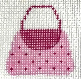 Cross-stitched pattern of a pink polka dot handbag with a red handle on a white background.