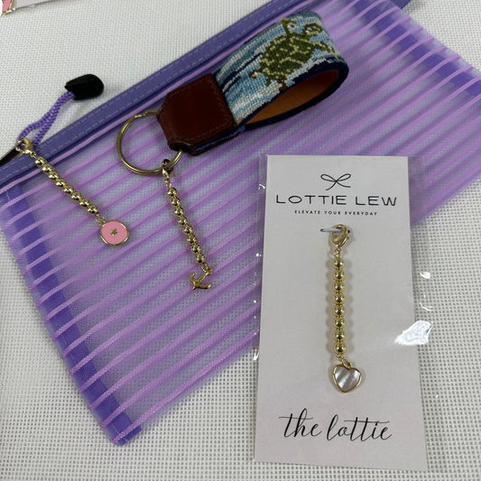 Gold charm keychain on a purple striped pouch with Lottie Lew branding