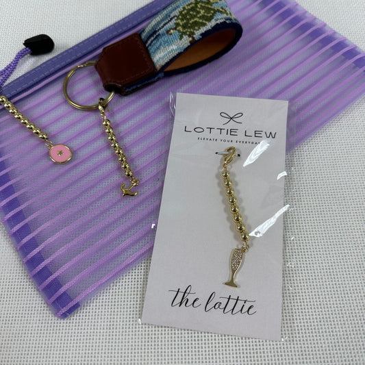 Gold bracelet with a charm on a card labeled 'Lottie Lew' against a striped background.