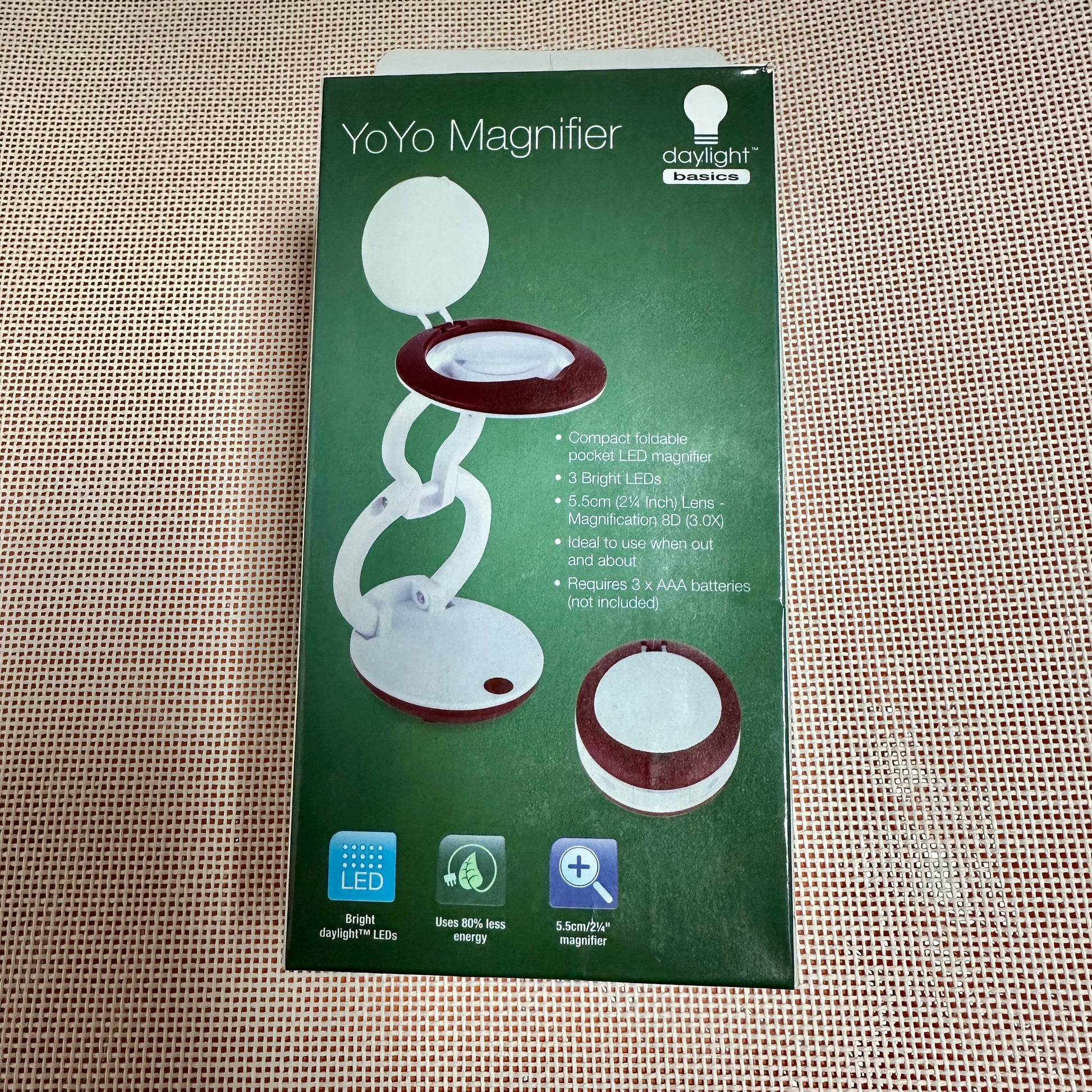 Green packaging of a YoYo Magnifier on a textured beige surface