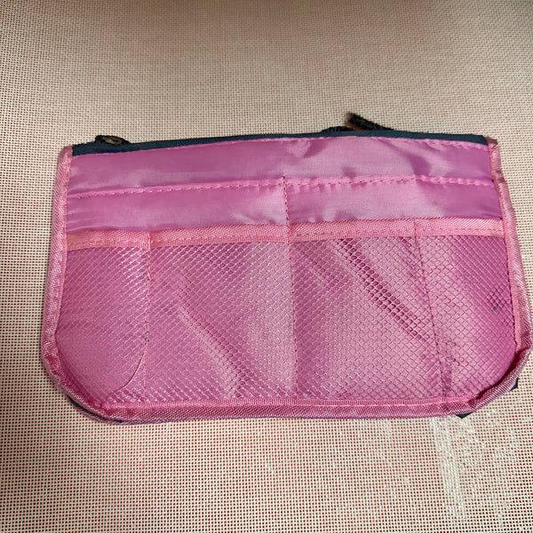 Pink mesh pouch on a beige textured surface
