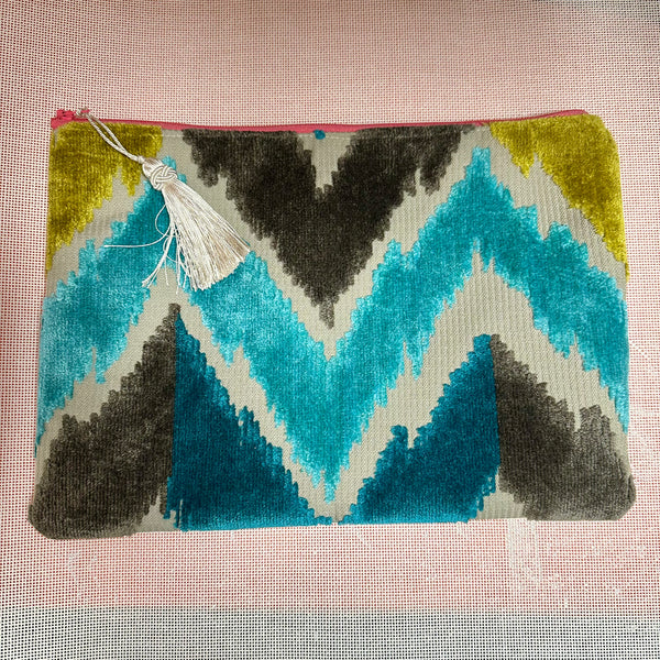 Colorful geometric pouch with a tassel on a textured pink background