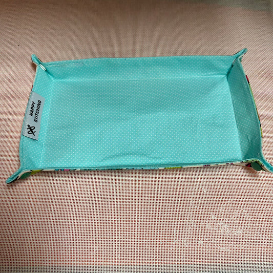 Turquoise fabric tray with a label on a beige surface