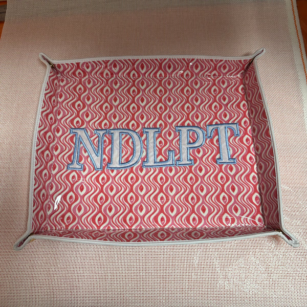 Rectangular fabric tray with red pattern and 'NDLPT' text on a beige surface