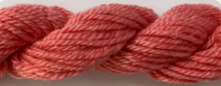 A close-up of a twisted skein of yarn in a dusty rose or muted coral pink color.