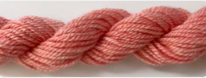 A close-up of a twisted skein of yarn in a soft dusty pink color.