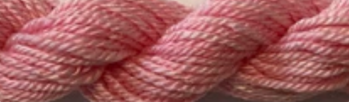 A close-up of a pink twisted yarn or thread skein filling the frame.
